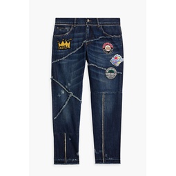 Tapered appliqued distressed denim jeans